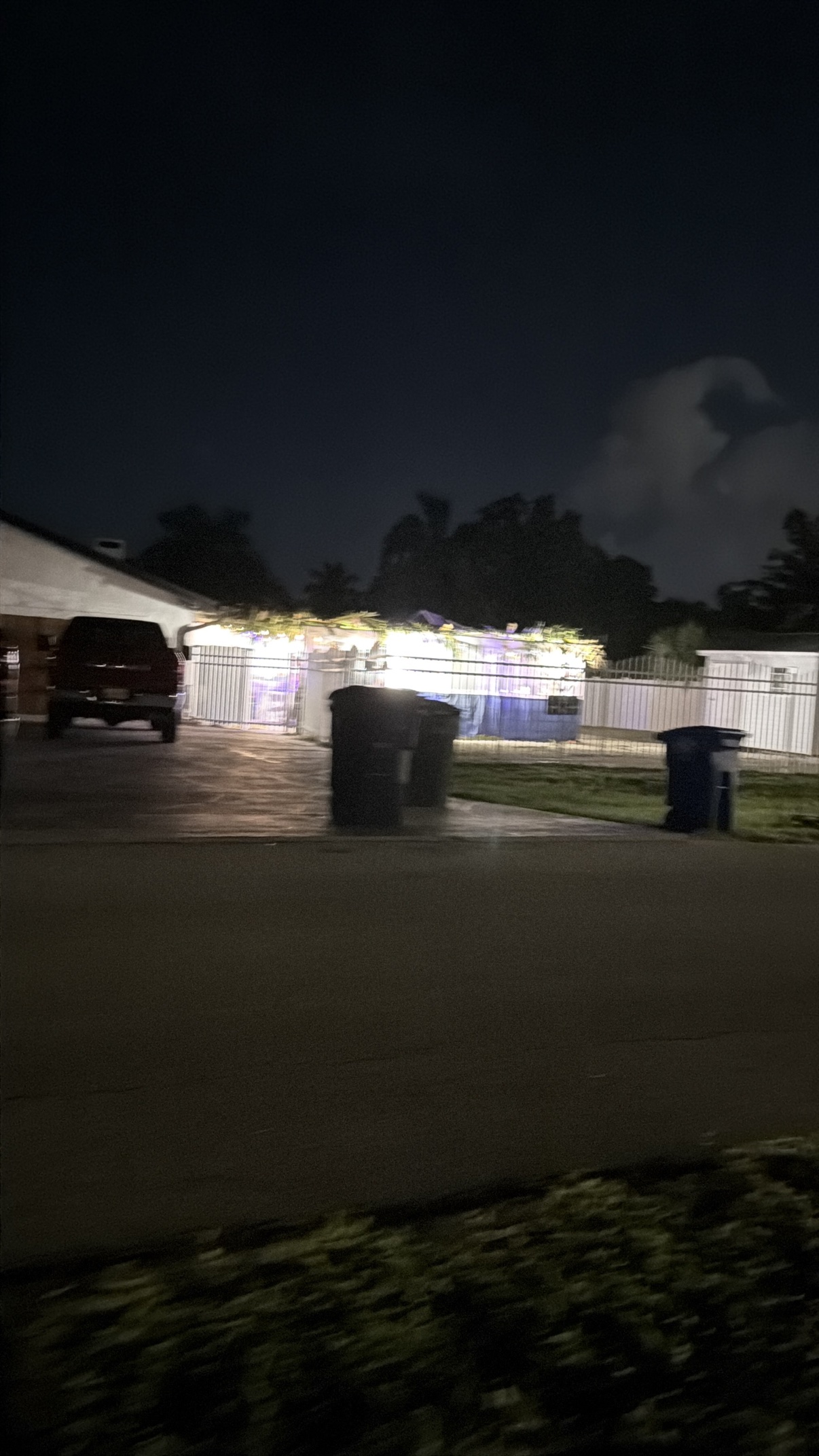 A neighbor's sukkah glowing with warm string lights at night
